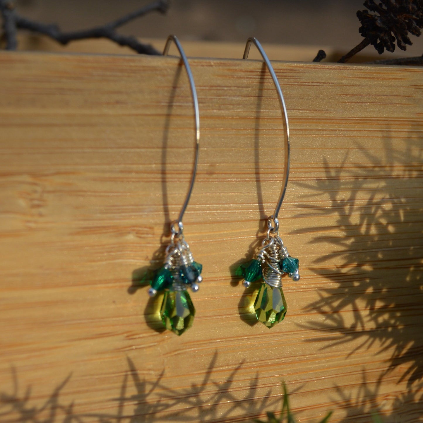 Sterling silver earrings with faceted Czech glass crystals in green and blue tones.