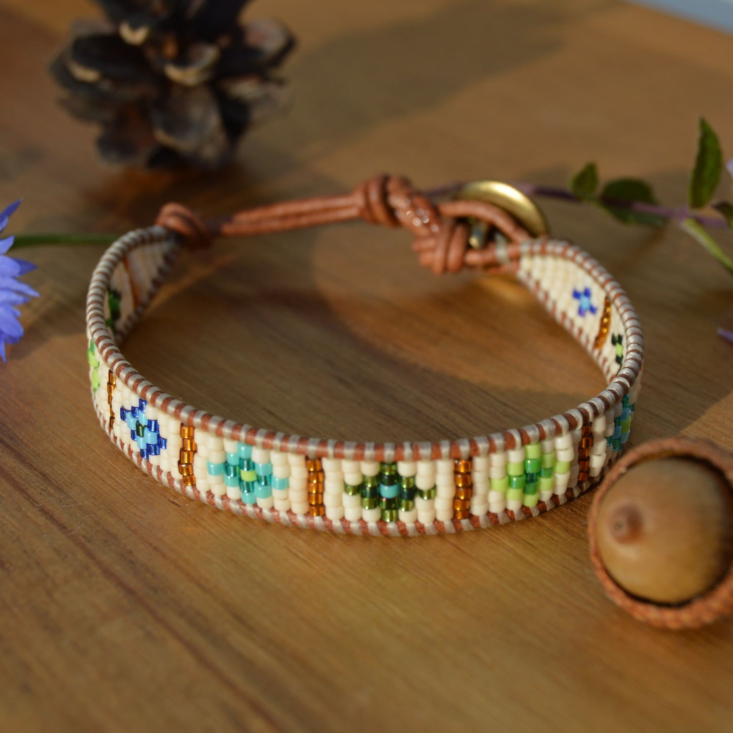 Leather wrap bracelet with woven seed beads in green & blue tones.